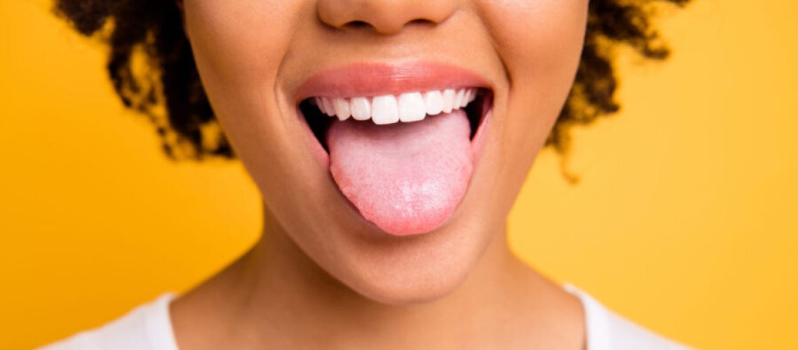 cropped closeup of Black woman sticking her tongue out against a yellow background